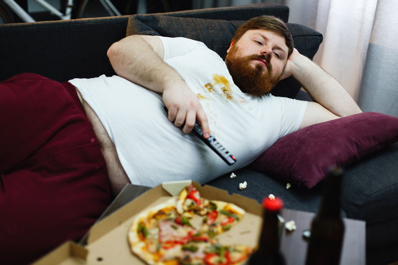 hombre-gordo-triste-miente-sofa-mira-tv
